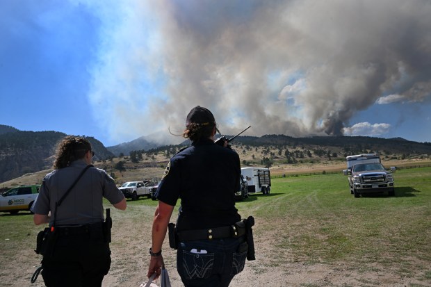 Andrea Maxwell, right, with the Larimer County Sheriff's posse, and Kayley McMurry, with the NOCO Animal Protection services talk on the radio as they head to their vehicles while keeping watchful eyes the Alexander Mountain fire burning west of Loveland on July 29, 2024. (Photo by Helen H. Richardson/The Denver Post)