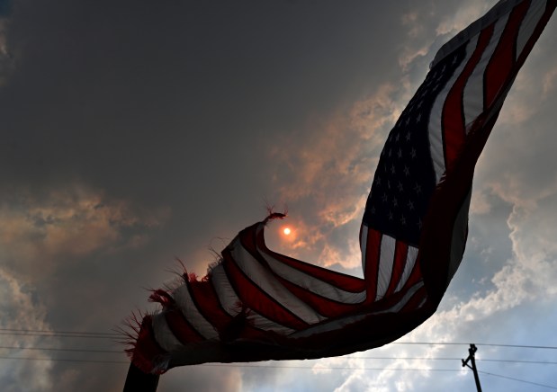 A tattered American flag blows in the wind along Glade Road west of Loveland on July 30, 2024. The Alexander Mountain Fire continues to burn in the background consuming over 5000 acres as of Tuesday night. (Photo by Helen H. Richardson/The Denver Post)