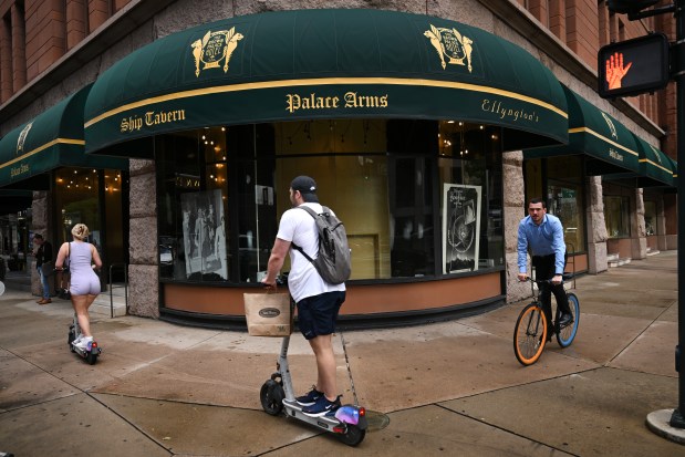 People on bikes and scooters pass by empty windows at the iconic Brown Palace Hotel in Denver on Sept. 4, 2024. (Photo by Helen H. Richardson/The Denver Post)