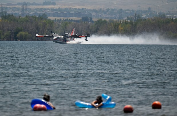 As beachgoers float in the water, an air tanker skims the waters of Chatfield Reservoir while refilling for the aerial fight against the Quarry fire in Jefferson County just west of Chatfield Reservoir on Wednesday, July 31, 2024. (Photo by Eric Lutzens/The Denver Post)