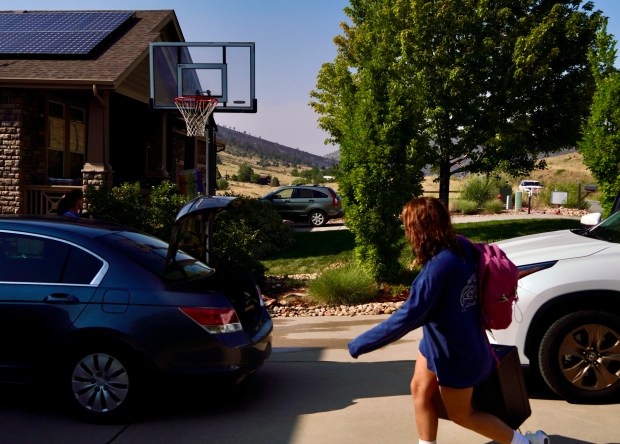 Genevieve Newell brings items into the garage after an evacuation order was lifted for their home in Lyons on Thursday, Aug. 1, 2024. Their home was a quarter mile away from where the fire was suppressed off of Stone Canyon Road, seen in the background. (Photo by Zachary Spindler-Krage/The Denver Post)