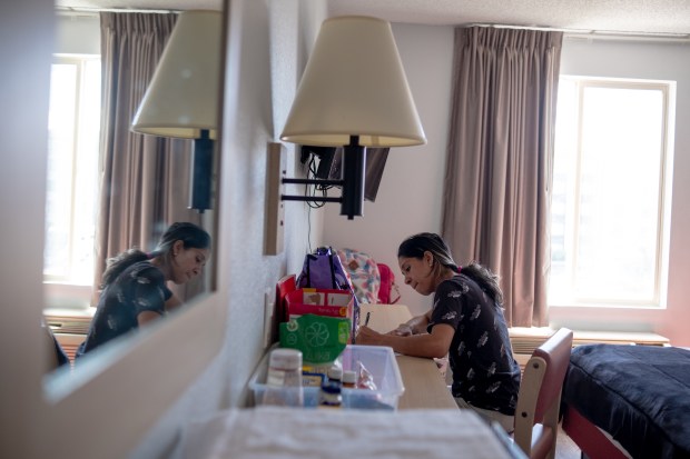 Andrea Fuenmayor, who has been homeless and living in a Motel 6 with her two children for two weeks, works on a school transportation assistance letter for her daughter in her motel room in Greenwood Village on Friday, Aug. 23, 2024. Fuenmayor and her children recently migrated from Venezuela. (Eli Imadali/Special to The Denver Post)