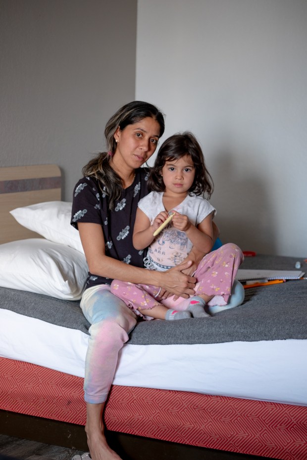 Andrea Fuenmayor and her daughter, Alexa Fuenmayor, 4, sit for a portrait in their Motel 6 room in Greenwood Village on Friday, Aug. 23, 2024. Fuenmayor and her two children, who migrated from Venezuela, are currently homeless have been living in the motel for two weeks. (Eli Imadali/Special to The Denver Post)